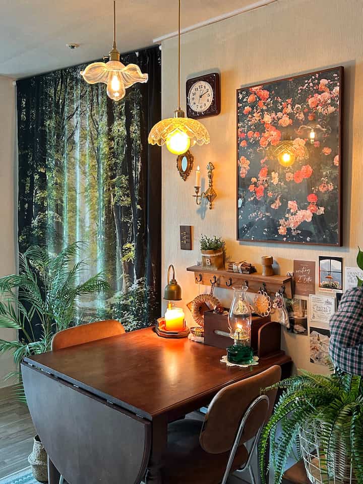 ブラウン調のダイニングルーム、木製ダイニングテーブルと椅子、森の柄カーテン、ヴィンテージの壁飾りと照明が配置された雰囲気のあるインテリア