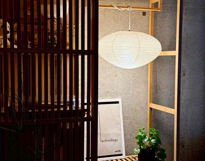 ナチュラルな色調と木目調が調和した小さな空間、中央上部にイサム・ノグチのアカリペンダントライトと植物が配置された温かみのあるインテリア