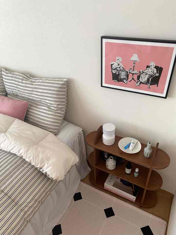 White and natural toned bedroom with striped pillows and vintage wall art, cozy and warm atmosphere