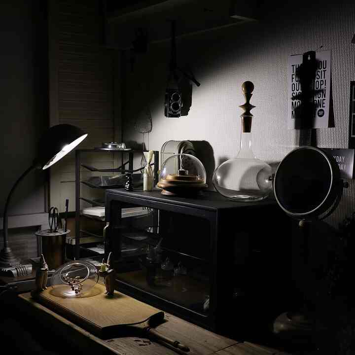 ウッドトーンのコーナー収納、ヴィンテージアイテムが並ぶ落ち着いた照明の雰囲気あるインテリア