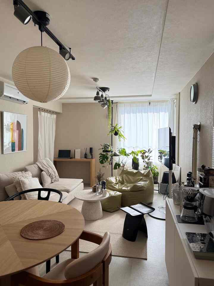 ベージュとナチュラルな色調の2LDKリビング、ソファと丸テーブル、植物が配置された雰囲気のある空間