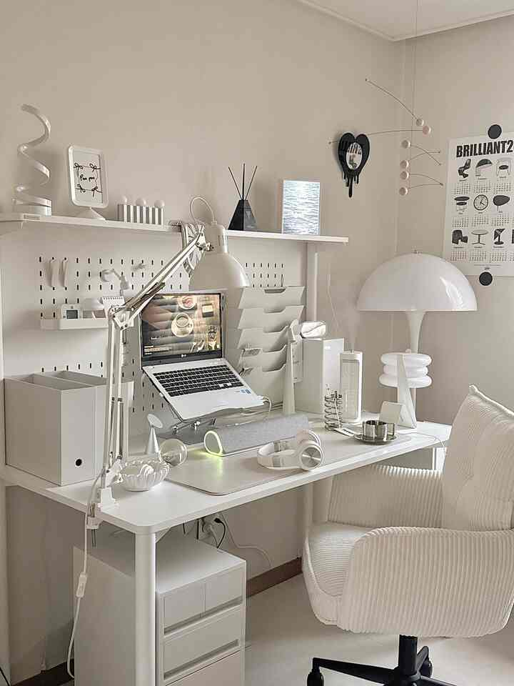 明るいホワイトトーンのホームオフィス空間、机上にノートパソコンと照明、快適なオフィスチェアが配置されたミニマルで現代的な雰囲気のインテリア