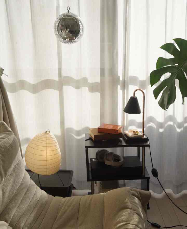 Beige and white toned living room featuring a cozy sofa and side table in a simple, comfortable setting