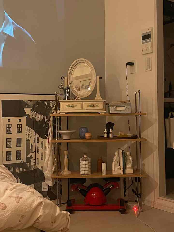 Warm beige and gray toned small single household bedroom with a poster on the wall and decorative shelf accessories