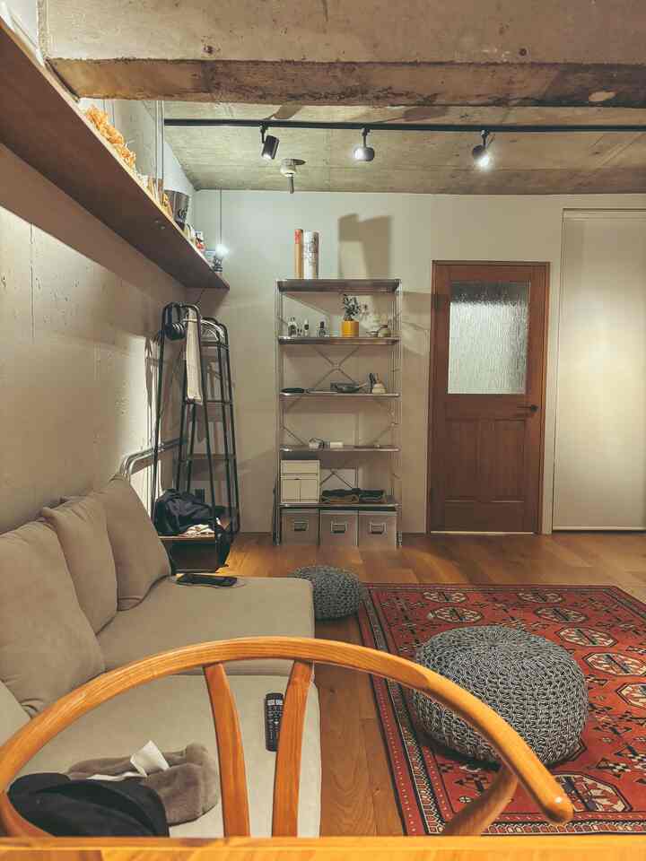 温かみのあるウッドトーンとナチュラルモダンスタイルの1LDKリビング、ベージュのソファとペルシャ風の赤いラグが調和した居心地の良い空間