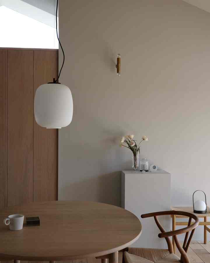 A simple, natural dining room with white and wood tones featuring a round dining table and Y-chair, creating a cozy atmosphere