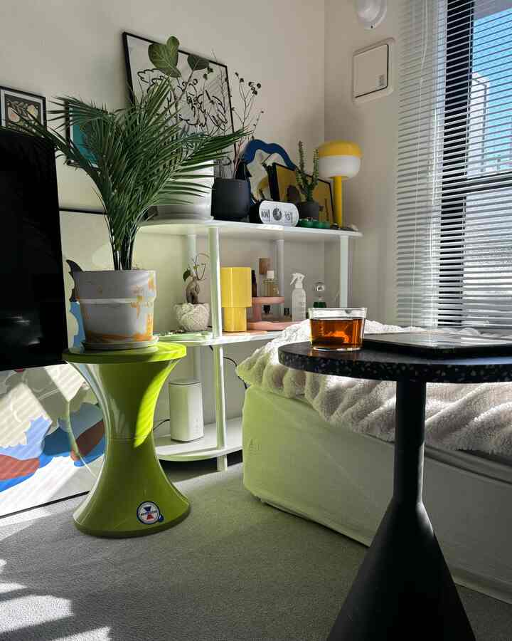 白い壁とベッドがある8畳のベランダ窓付き一人暮らしの寝室、緑の植物とブラインドがアクセントの落ち着いた空間