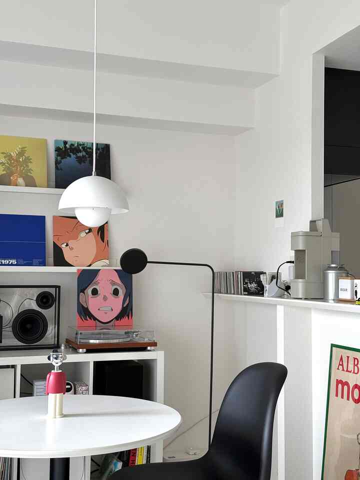 白黒のトーンのリビング、ペンダントライトとレコードプレーヤーが配置されたミニマルな音楽鑑賞のスペース