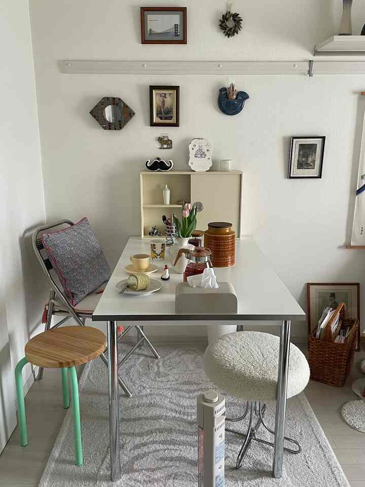 White and natural toned 1K studio living room featuring a minimal dining table and stools with a cozy atmosphere