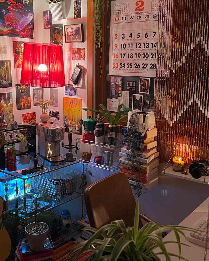 暖かい赤い照明が映えるレトロ風のカフェ兼在宅勤務スペース、小さな部屋に壁掛けカレンダーとポスターが飾られている