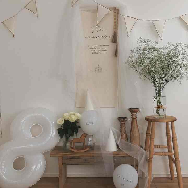 ベージュと木目調の子供部屋、パステル調のパーティー装飾とガーランド、木製スツールが配置された雰囲気のあるインテリア