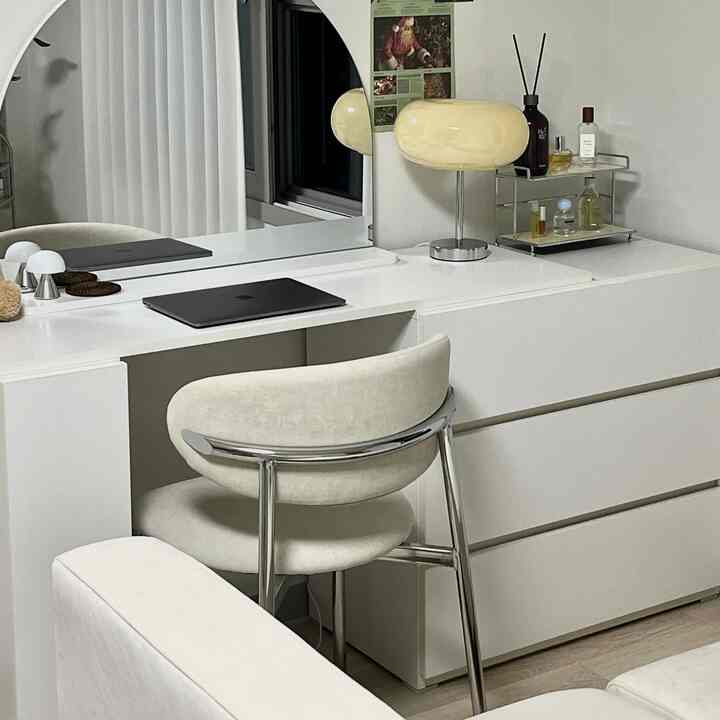 ミッドセンチュリーモダンスタイルのホワイトトーンの化粧台空間、クロームフレームのアームチェアと独特なテーブルランプが配置された清潔感あるインテリア