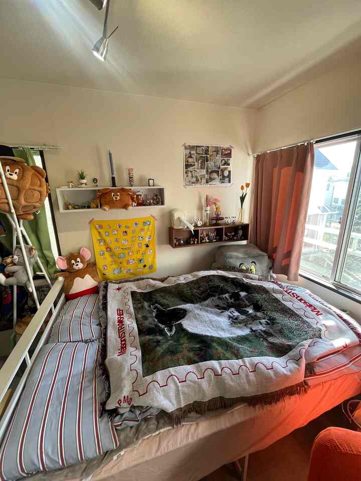 Cozy bedroom with white walls and warm pink curtains, featuring Tom & Jerry character blanket and plush toys for a single occupant