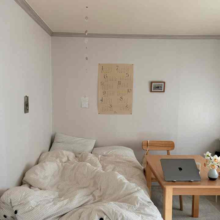 明るくナチュラルトーンの6畳寝室、ストライプ寝具と木製テーブルが調和したシンプルな雰囲気のインテリア