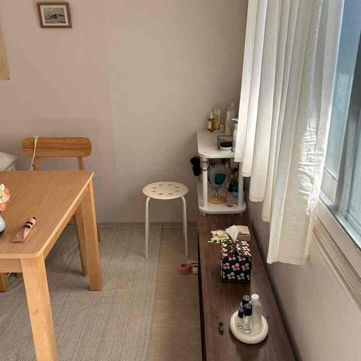 ナチュラルトーンのダイニング、木製のテーブルと椅子、白いカーテンが配置された暖かい雰囲気の空間