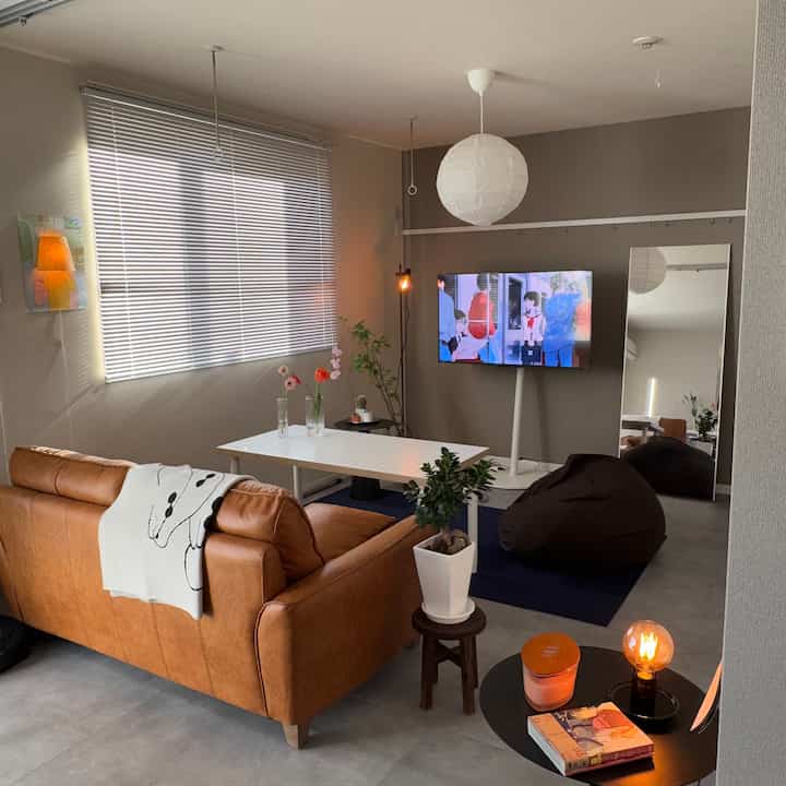 Gray and brown toned living room featuring a large brown sofa and white dining table in a modern setting