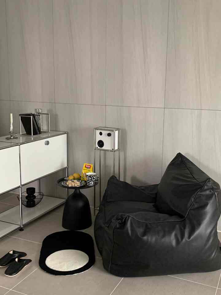 Modern gray and black toned living room featuring a soft black bean bag sofa and side table with cozy atmosphere