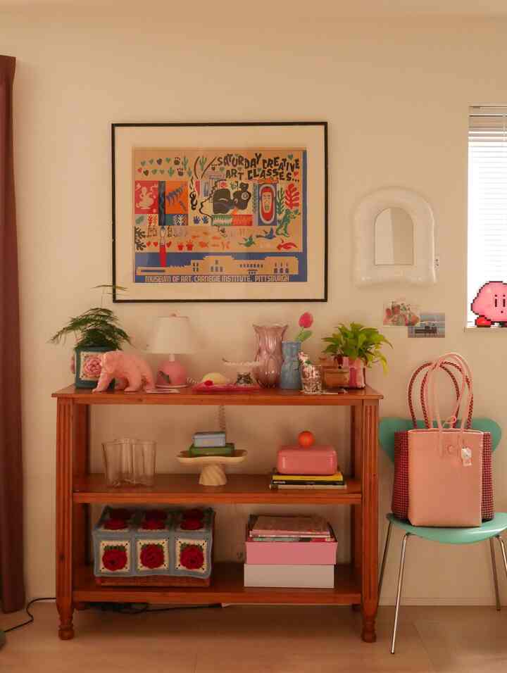 温かみのあるナチュラルカラーとピンクの装飾が調和したヴィンテージ風の棚と多彩な小物が置かれた印象的なインテリア