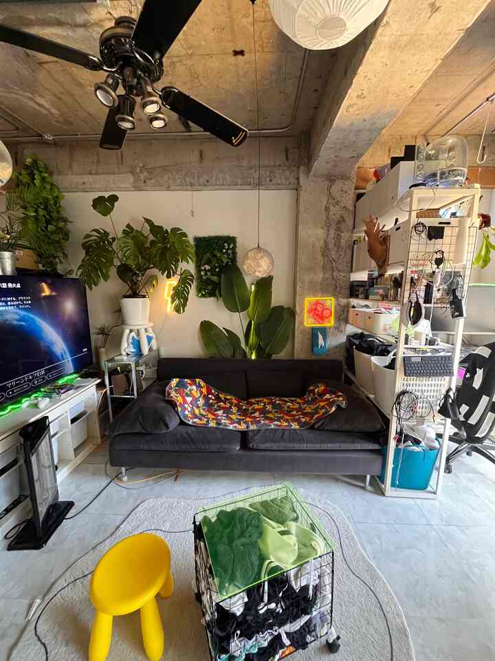 黒とナチュラルカラーのリビング、黄色のスツールと植物が配されたモダンでインダストリアルな雰囲気のある空間