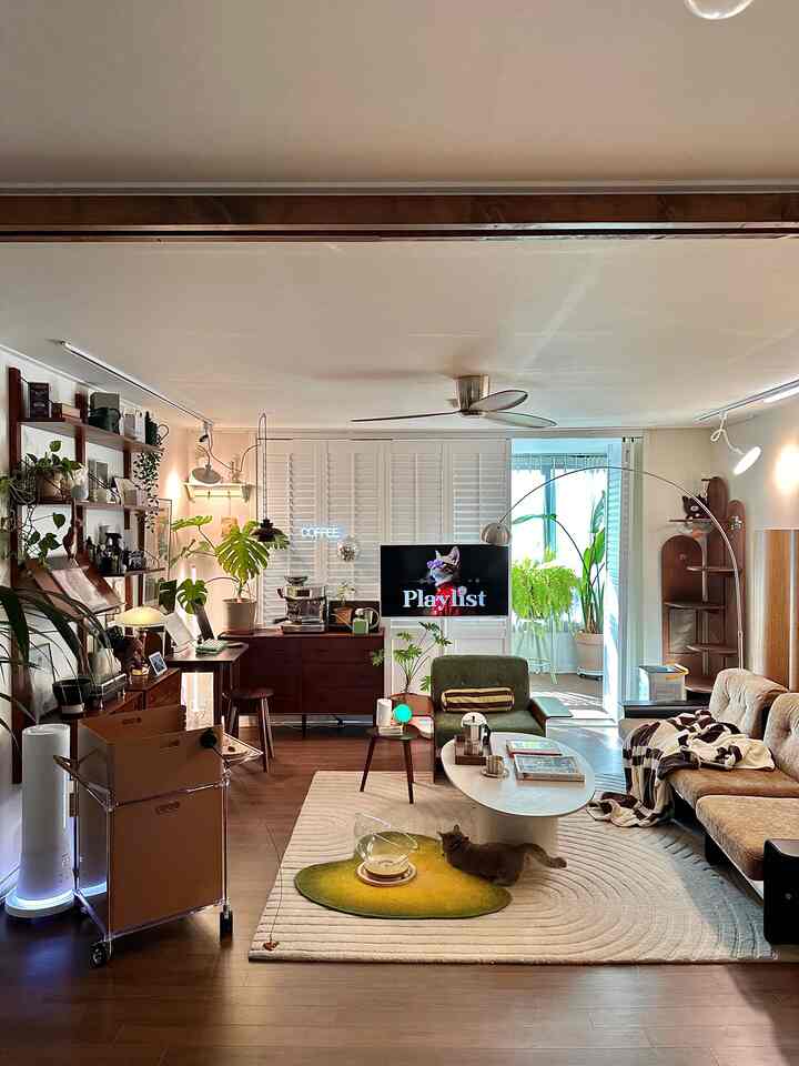 暖かいブラウンとグリーンのトーンのリビング、ヴィンテージスタイルのソファと豊富な植物が配置された雰囲気のある空間