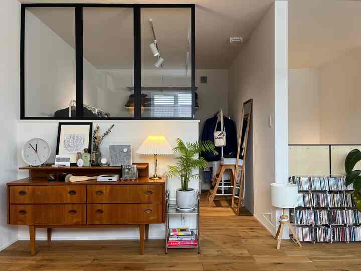 Walk-in closet space featuring vintage wooden furniture and interior glass window with white walls and wood tone flooring