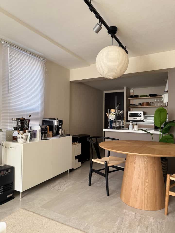 白と木目調が調和したダイニングルーム、丸いダイニングテーブルとペンダントライトが配置された北欧風の雰囲気あるインテリア