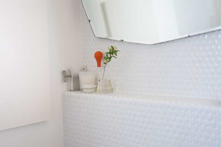 White-toned bathroom featuring circular tiles and minimal accessories with a modern interior feel