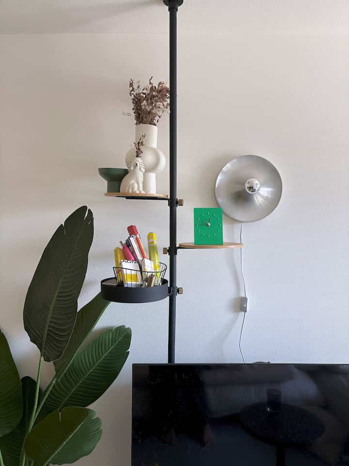 Natural tone single household 1K bedroom featuring TV, black shelving pole, and wall sconce in a cozy space