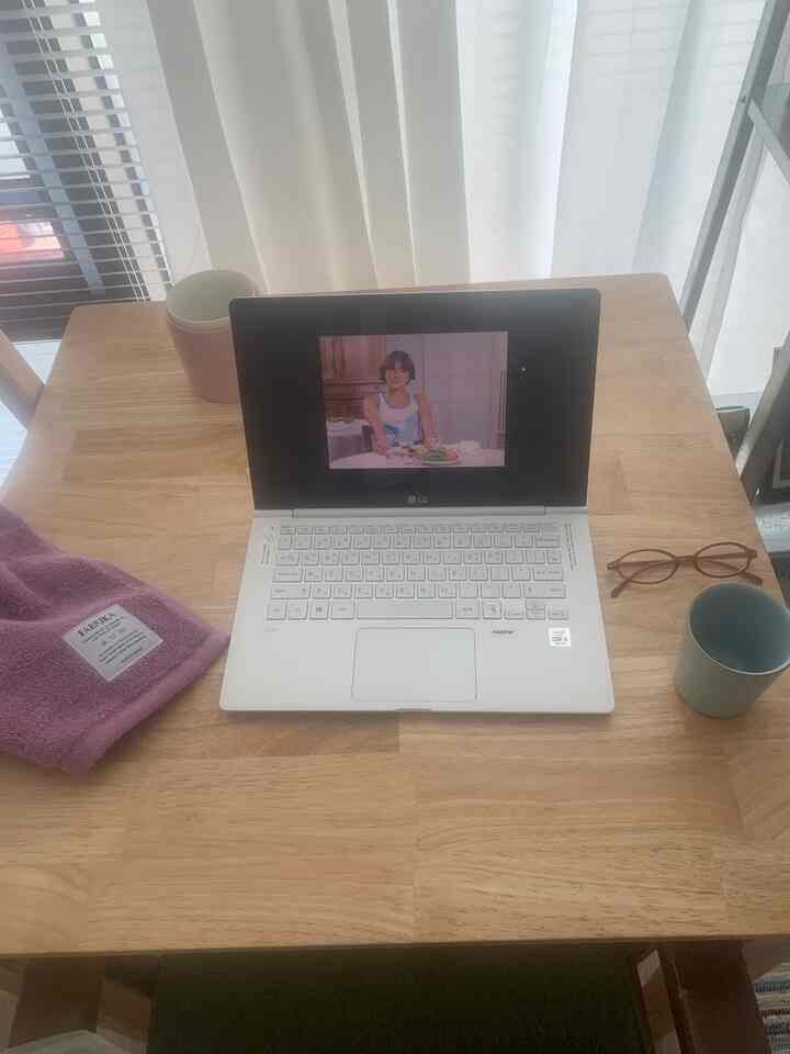 ナチュラルな木製デスクにノートパソコンとマグカップ、メガネが置かれた雰囲気のあるホームオフィス