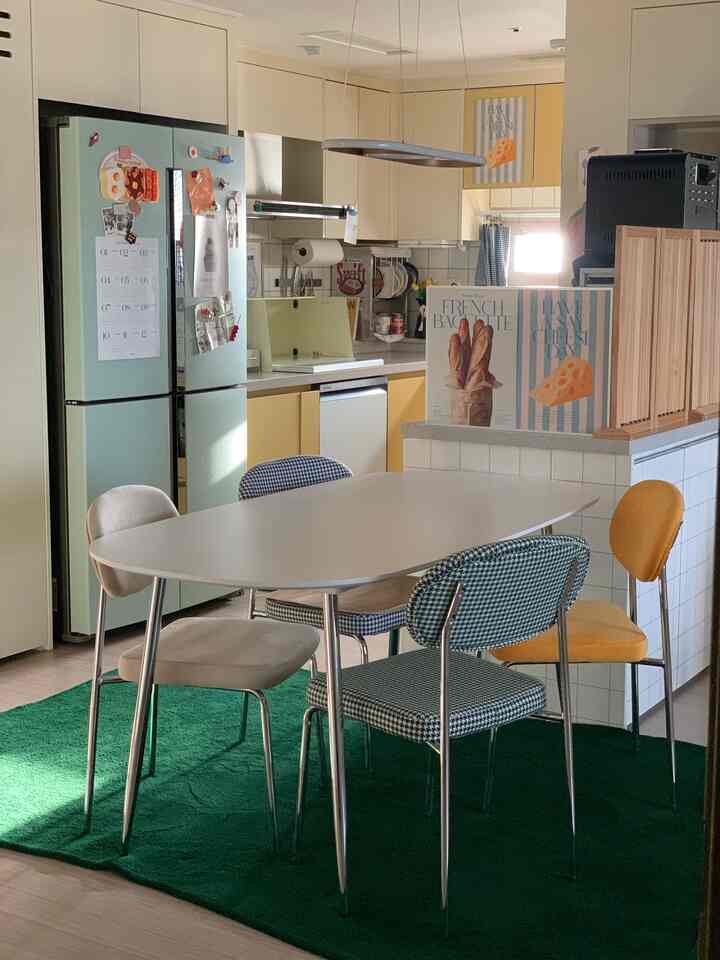 黄色とナチュラルトーンの調和したキッチン、様々な椅子とダイニングテーブルが配置された雰囲気のあるインテリア