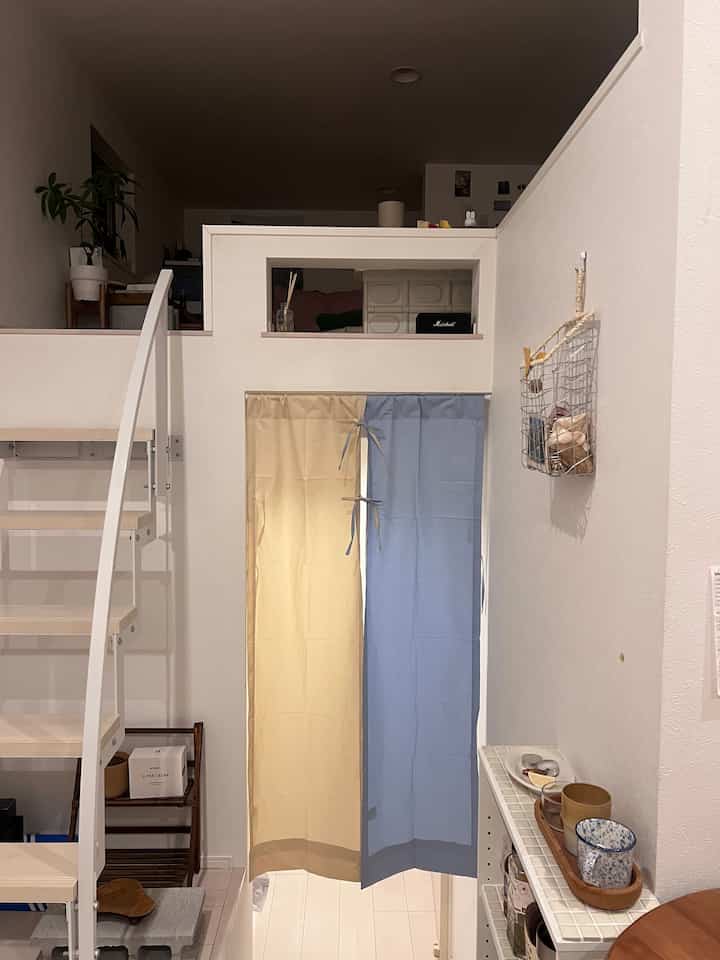 パステル色調のロフト付きのシンプルでモダンな一人暮らし用リビングとキッチン空間