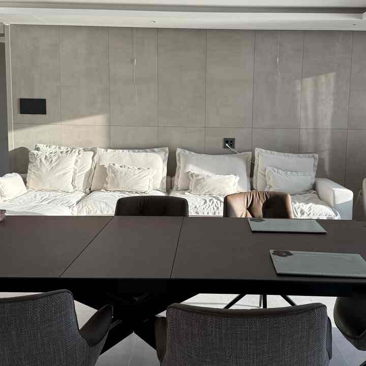 Bright white-toned living room featuring a 4-person white sectional sofa and dark brown dining table in a modern home office setup