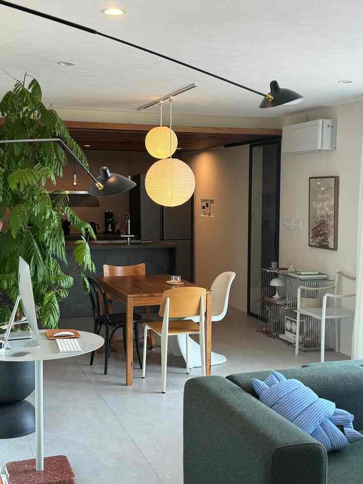 ウッドトーンとネイビーが調和したミッドセンチュリーモダンのダイニングリビング、ペンダントライトとフロアランプを配した印象的な空間