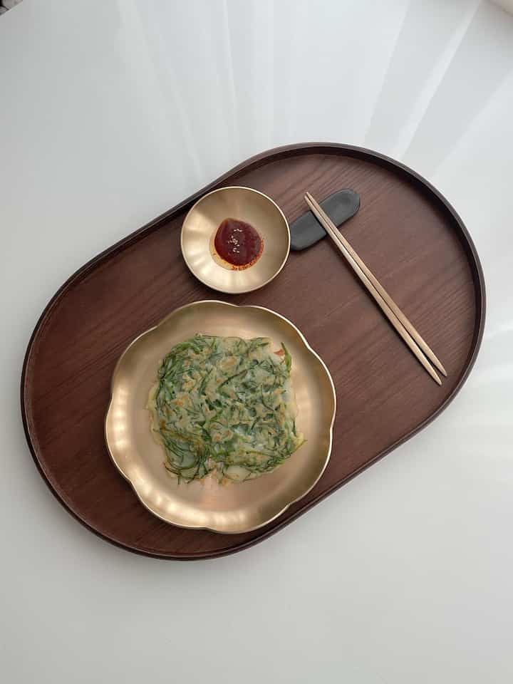 Simple dining set on dark brown wood-tone oval tray with gold-toned tableware