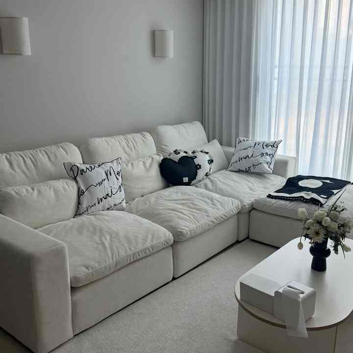 ホワイトとブラックを基調としたリビング、ふかふかのソファとクッションが映えるモダンで落ち着いた空間