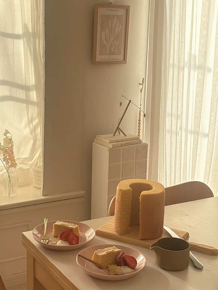 Warm beige toned cozy Nordic-style dining space featuring cake on plates and a small pitcher, evoking a relaxed home cafe atmosphere