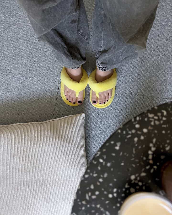 ナチュラルカラーの8畳ワンルームの床に、黄色の厚手のタオルスリッパとベージュのクッションが置かれた印象的な空間