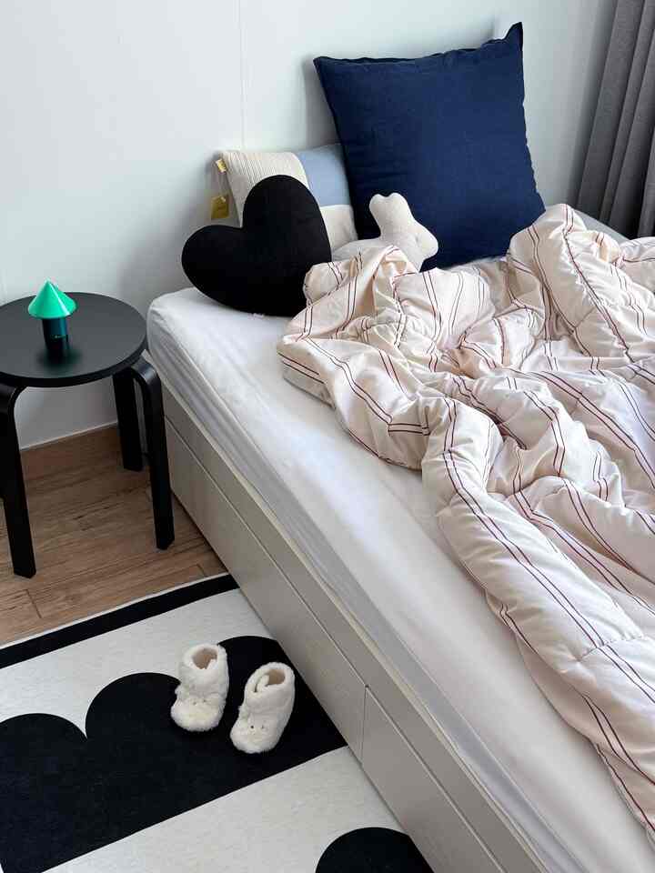 白とネイビートーンの子供部屋、シンプルな白の収納ベッドと多様なクッションが配置された清潔感のあるインテリア