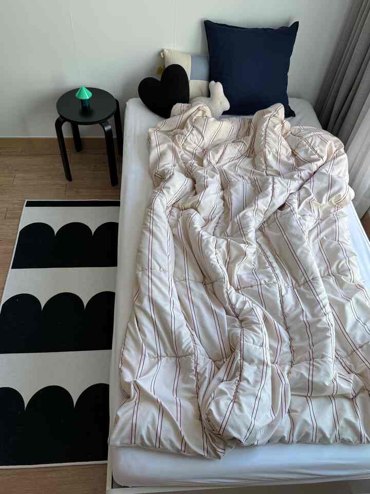 White and navy-toned bedroom featuring a simple bed, stool, and Nordic-style elements with a calm atmosphere