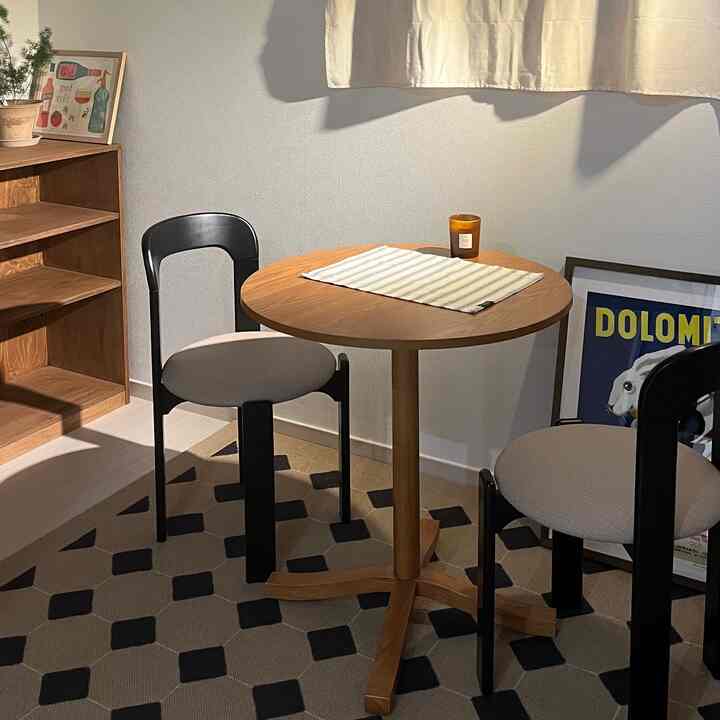 Natural wood tones and black accented two-person dining room with simple, cozy ambiance in a newlywed interior