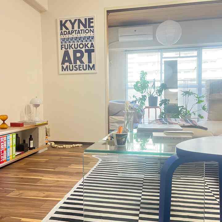 Natural-toned living room with transparent glass coffee table and blue stool in a bright cozy space