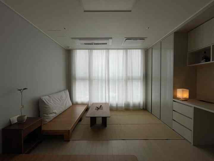 Natural wood tone studio apartment featuring a simple wooden sofa bed and tatami mat, embodying a Zen style minimalistic interior