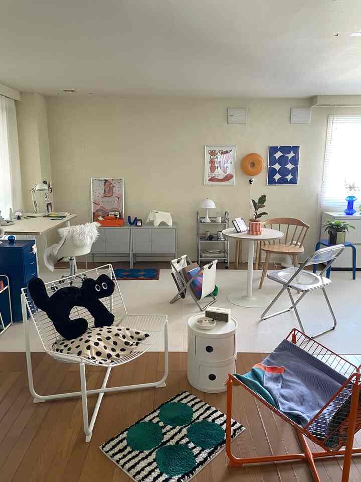 白とオレンジのトーンが調和した1LDKのリビング、ミッドセンチュリーモダンスタイルの椅子やデスク、カーペットが配置された印象的な空間