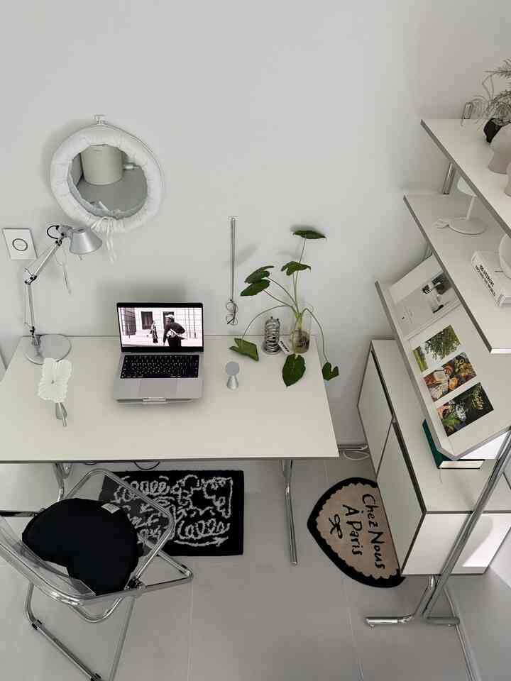 ホワイトとグレーのトーンが特徴のコンパクトな書斎、白いデスクと棚、シルバーのテーブルランプが配置されたミニマルで清潔感のあるインテリア