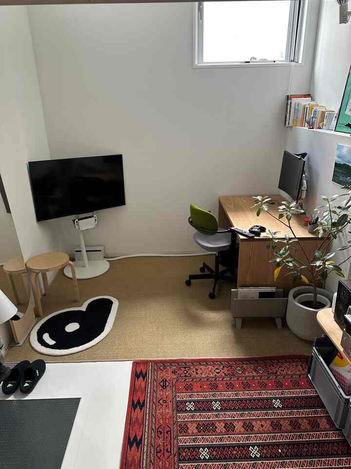 White and brown toned home office space featuring desk, chair, wall-mounted TV, and rugs creating a calm atmosphere