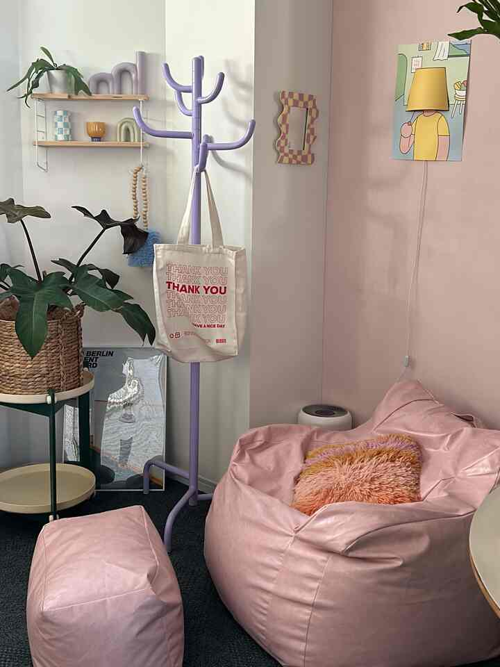 ピンク色調のリビング、ビーズクッションソファとパープルのコートハンガーが配置された印象的な空間