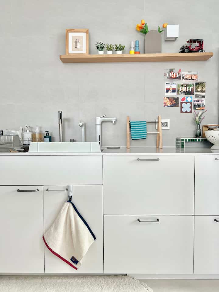 White tonal kitchen with sink and towel holders neatly arranged, featuring natural accents and a clean atmosphere