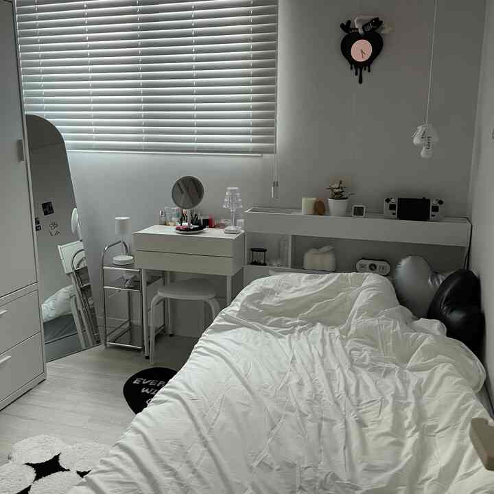 ホワイトとグレーのトーンのコンパクトな寝室、ベッドとドレッサーが配置された清潔感のある自然な空間
