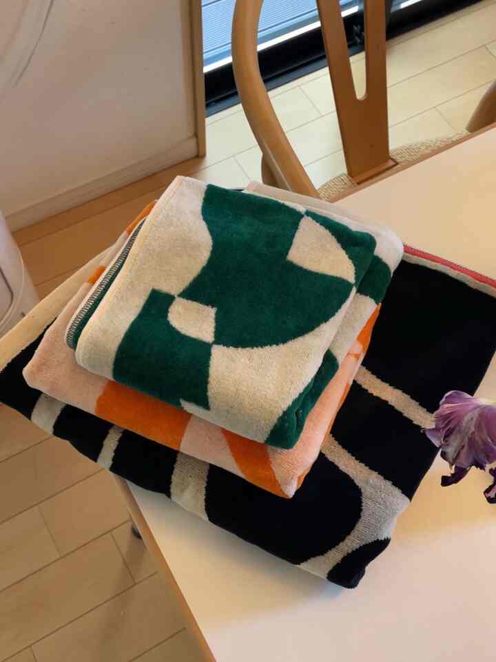 ナチュラルな木目調と白いテーブルがあるダイニングルーム、折りたたまれたカラフルなデザインのタオルが積まれている雰囲気のあるインテリア