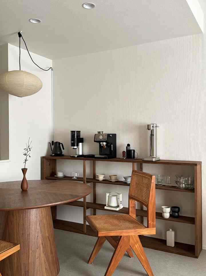 白を基調とした壁に木目調家具が配されたダイニング、丸い木製テーブルと籐の椅子が印象的なシンプルで温かみのあるインテリア